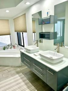 La salle de bains est pourvue de 2 lavabos, d'une baignoire et d'une baignoire. dans l'établissement Luxurious pool home in Palm Beach County, Florida, à Wellington