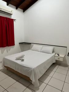sypialnia z białym łóżkiem z czerwoną zasłoną w obiekcie HOTEL MARAMBAIA w mieście Ponta Porã