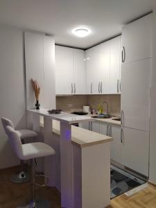 a kitchen with white cabinets and a sink and a chair at Apartman Mančić in Pirot
