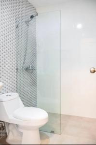 a bathroom with a toilet and a glass shower at Espléndida y Acogedora Villa con Vista a las Montañas y Nuestro Bello Pueblo in Jarabacoa