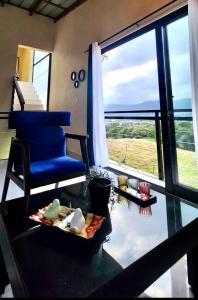 una mesa de cristal con una silla azul y una ventana en Espléndida y Acogedora Villa con Vista a las Montañas y Nuestro Bello Pueblo, en Jarabacoa
