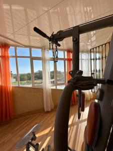 Apartamento puestas de sol في شيكلانا دي لا فرونتيرا: غرفة مع صالة ألعاب رياضية مع آلة ركض ونوافذ