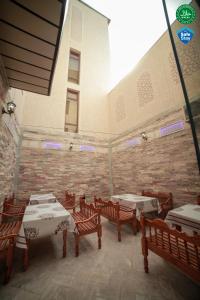 um pátio com mesas e cadeiras e uma parede de tijolos em Мы открылись! Hotel Guli em Bukhara