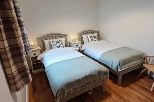 Duas camas num quarto com pisos de madeira em Foxglove Lodge 