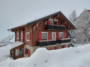 a snow covered house with red doors and windows at Chant du Torrent: 12 pers. idéal pour les familles in Nendaz