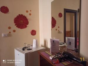 Habitación con escritorio con espejo y flores rojas en la pared. en Hotel Kurtabeg, en Shkodër