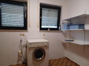 a washing machine in a bathroom with two windows at Monteurwohnung Wiedenmann in Koetz 