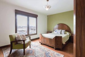 a bedroom with a bed and a chair and a window at Penthouse with terrace at the Old City in Montevideo