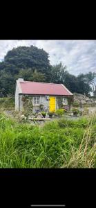 a small house with a yellow door in a field at The Nest Quaint Luxury Cottage Getaway in Tiragarvan