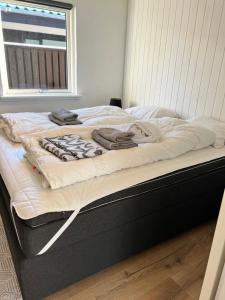 uma cama com lençóis brancos e toalhas em Huset ved søen tæt på Herning og MCH og boxen 90 m2 em Sunds