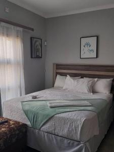 a bedroom with a large bed with a window at Serene Cottage in Francistown