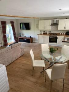 a kitchen and living room with a glass table and chairs at Mendip Edge Retreat in Farrington Gurney