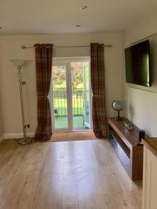a living room with a television and a sliding glass door at Mendip Edge Retreat in Farrington Gurney