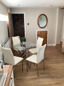 a dining room with a glass table and white chairs at Mendip Edge Retreat in Farrington Gurney