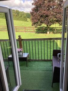 einen Balkon mit einem Tisch und Blick auf ein Feld in der Unterkunft Mendip Edge Retreat in Farrington Gurney