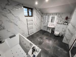 bagno con pareti in marmo, lavandino e servizi igienici di Hotel Laktaši a Laktaši