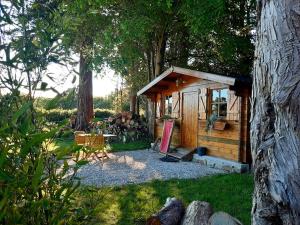 a small wooden cabin with a table and a chair at Le Chalet du Clos Giot in Saint-Vaast-la-Hougue