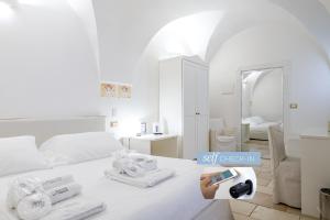 a white room with a bed with towels and a mirror at Dimora Dell'Osanna Raro Villas Smart Rooms Collection in Carovigno