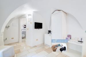 a white bathroom with a tv on a wall at Dimora Dell'Osanna Raro Villas Smart Rooms Collection in Carovigno