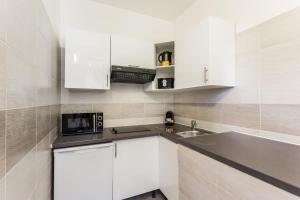 uma cozinha com armários brancos, um lavatório e um micro-ondas em Beautiful Apartment 6 P - Village d'Auteuil em Paris