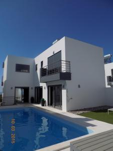 uma casa branca com uma piscina em frente em Villa Valcha na Lourinhã