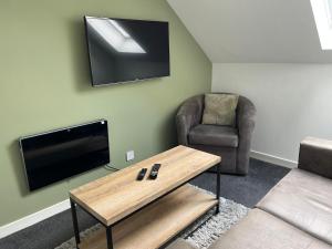 ein Wohnzimmer mit einem TV, einem Stuhl und einem Couchtisch in der Unterkunft Dunbar High Street One Bedroom Apartment in Dunbar