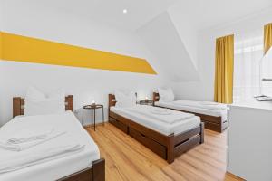 two beds in a room with white walls and wooden floors at GoldenHome - Comfy&Big - FootballTable - BarbecueTerrace - Nähe Autobahn, Therme, Stadion in Sinsheim