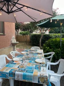 un tavolo con sedie bianche e un ombrellone di Appartamento Rivarola Ulivo a Carasco