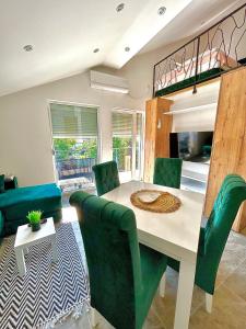 uma sala de jantar com uma mesa e cadeiras verdes em Apartman Viny em Sokobanja