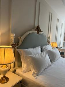 a bed with white sheets and pillows with two lamps at SOL INVICTUS Boutique Hotel Durres Albania in Durrës