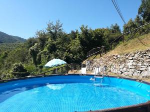 una piscina con sombrilla y montaña en La casa del girasole en Piazza al Serchio