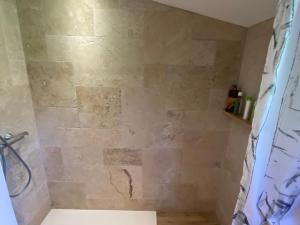 a bathroom with a shower with a stone wall at Apatam-Montigny, bord du Loing in Bourron-Marlotte +34 photos