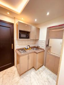 a small kitchen with a sink and a microwave at El Mansour Hotel apartmen 74 in Mansoura