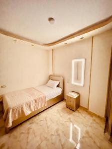 a small bedroom with a bed and a night stand at El Mansour Hotel apartmen 74 in Mansoura