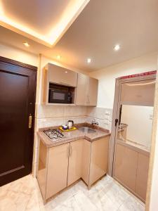 a small kitchen with a sink and a microwave at El Mansour Hotel apartmen 74 in Mansoura