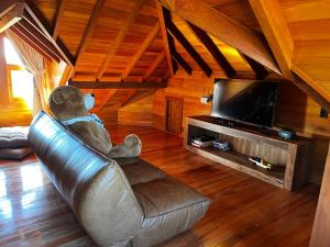 a teddy bear sitting on a leather couch in front of a television at Tenuta Bergamaschi in São Joaquim