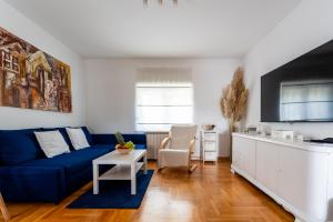 a living room with a blue couch and a kitchen at Apartman Borik in Bjelovar