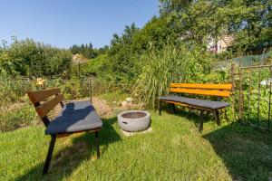 zwei Bänke im Gras im Garten in der Unterkunft V podkroví Luhačovice in Luhačovice