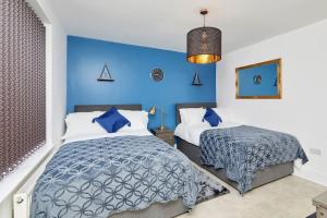 3 Bed Notts City Centre Town House - Free parking في نوتينغهام: غرفة نوم بسريرين وجدار ازرق