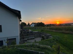 una puesta de sol sobre un jardín con un edificio y una casa en Haus am Wald, en Schrozberg