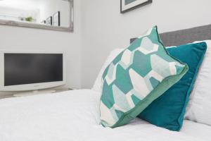 uma almofada verde e branca sentada numa cama com uma televisão em 3 Bed Notts City Centre Town House - Free parking em Nottingham