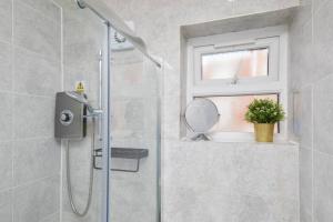 ein Bad mit einer Dusche mit einem Spiegel und einem Fenster in der Unterkunft 3 Bed Notts City Centre Town House - Free parking in Nottingham