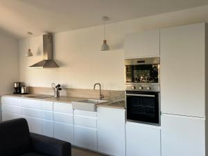 een keuken met witte kasten, een wastafel en een oven bij L’Oasis in Machecoul