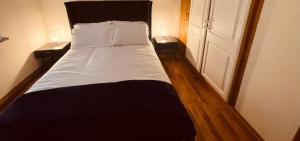 River Cottage في مولينجار: غرفة نوم بسرير مع مواقف ليلتين وباب