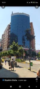 a woman walking down a street in front of a tall building at Selvia Apartament in Tirana