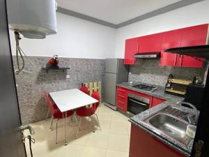 a kitchen with red cabinets and a table and a sink at Appartement avec piscine privée à Martil in Martil