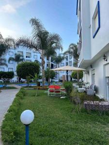 a yard with a table and chairs and a building at Appartement avec piscine privée à Martil in Martil