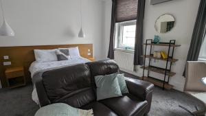 a living room with a bed and a leather couch at Captivating 1-Bed apartment Merthyr Tydfil - in Merthyr Tydfil