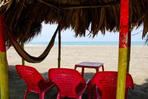 two red chairs and a table on the beach at Apartamento a unos pasos de la playa in Cartagena de Indias