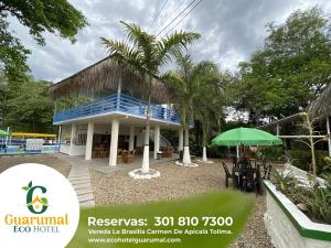 a resort with a blue building with a palm tree at Eco Hotel Guarumal in Carmen de Apicalá